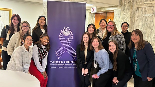 Georgetown biomedical students and Professor Tomoko Steen stand around the banner for the "Cancer Frontiers" symposium in the Medical and Dental Building